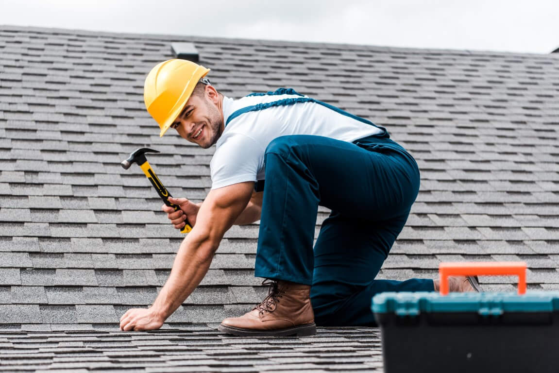 Worker nailing shingles on roof